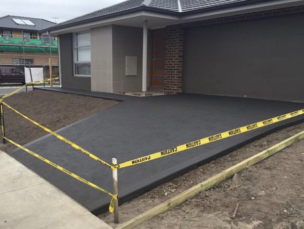 Freshly poured charcoal driveway at a new home, with caution tape still up while it cures