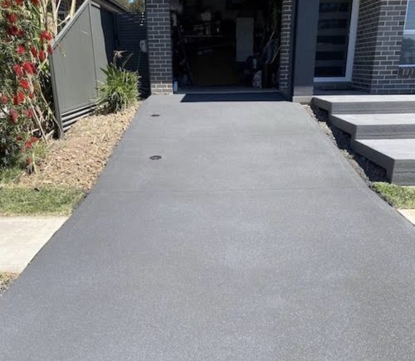 Charcoal concrete driveway beside the front steps of a new home
