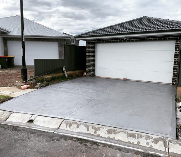 Grey concrete driveway with saw-cut joints in front of a double garage