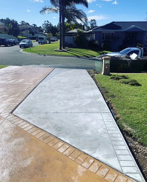 Concrete driveway with a swirl finish and a stamped brick-pattern border, running down to the street