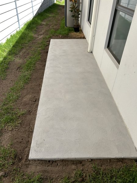 Concrete side path and slab with a swirl finish beside a house