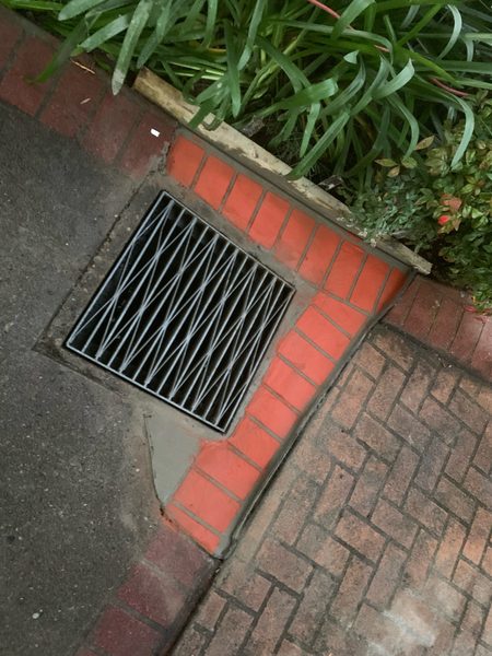 Concrete repair around a stormwater grate between brick paving